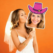 Woman in a wedding dress holding a cutout of a woman wearing a pink cowboy hat against an orange background