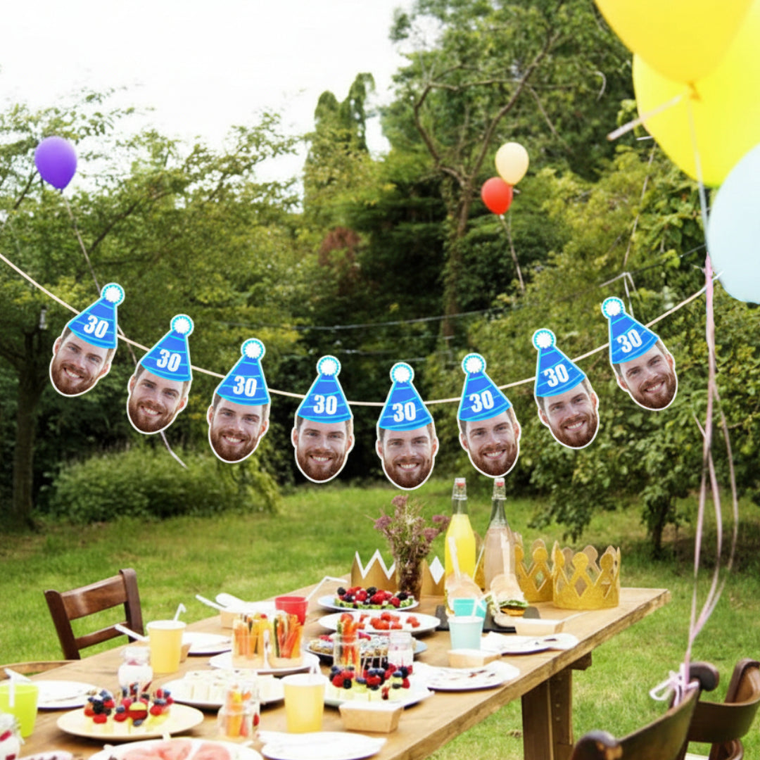 Outdoor birthday party setup with table, balloons, and face banners.