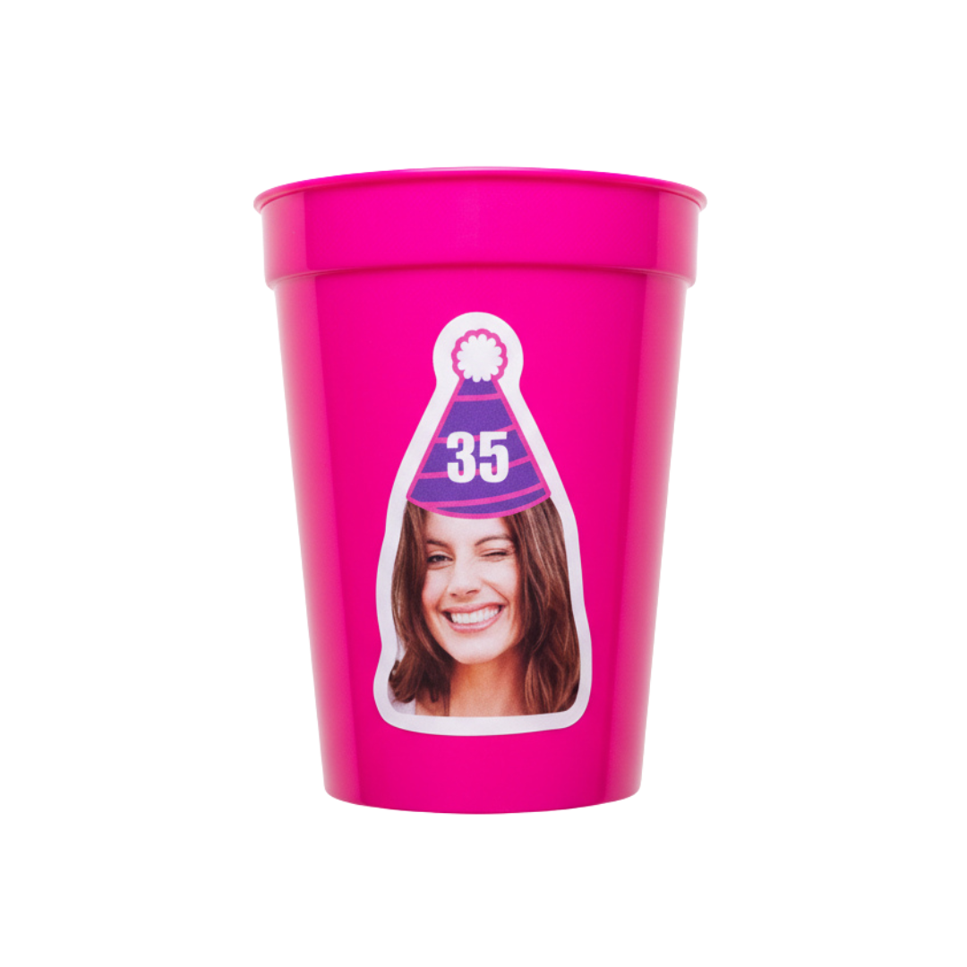 Pink plastic cup with a printed design of a woman wearing a party hat on a white background